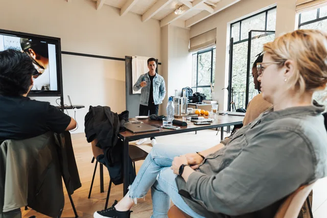 A group of professionals engaged in a dynamic presentation in a bright, modern office setting. Influencer management: commission vs retainer for creators
