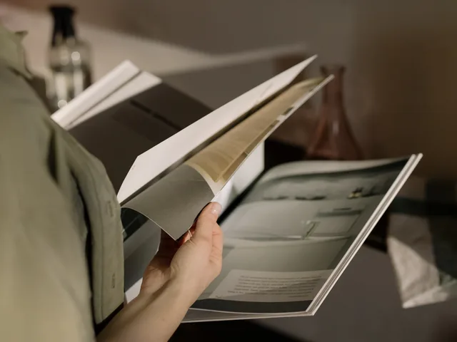 Close-up of a person flipping through a magazine indoors with soft lighting. Talent management: reading an agency launch review in England