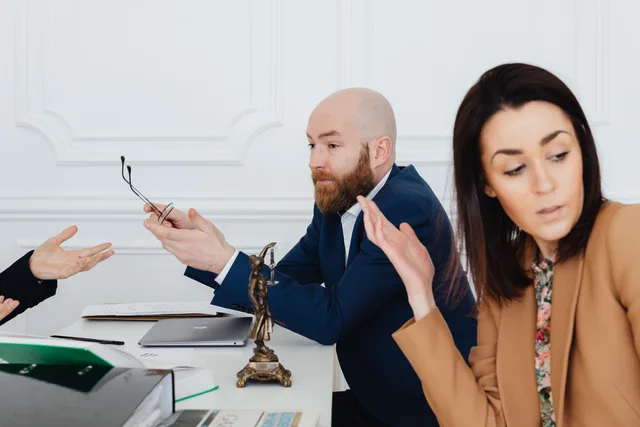 Three adults in a heated discussion with legal documents, indoors. Talent agencies risk scenarios, triggers, owners and first actions