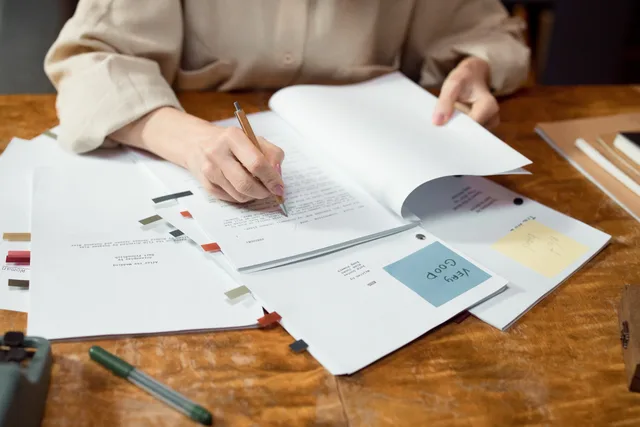 Close-up of hands writing and organizing documents on a wooden desk. Talent management strategy: what your agency will refuse